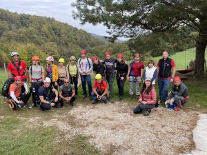 Alpinistička i orijentacijska vježba na Okiću i Terihajima Treći vikend planinarske škole donio nam je alpinističke i orijentacijske vježbe. Na maglovito subotnje jutro uputili smo se prema Terihajima, ali nas vrijeme nije obeshrabrilo jer smo naučili da se na većim visinama oblaci raščišćavaju. Tako je i bilo, na sunčanim Terihajima počeli smo s orijentacijskim vježbama. Nakon utvrđivanja znanja o kompasu i karti dobili smo zadatak pronaći 5 kontrolnih točaka na nemarkiranom terenu. Na početku smo bili malo zbunjeni i više se oslanjali na našu voditeljicu koja nam je spremno odgovarala na pitanja. No nakon početnog uhodavanja, vrlo brzo smo shvatili kako i šta trebamo raditi. Dok smo tražili kontrolne točke, s orijentacijske karte čitali smo i najmanja obilježja poput oveće stijene ili raslinja. Svatko od nas samostalno nas je vodio do barem jedne točke i svi su zadatak odradili uspješno. Nakon pronalaska svih točaka, uputili smo se do Okića gdje su nas dočekali naši alpinisti. Prvi zadatak bio je penjanje po stijeni. Svima nam je to bio prvi susret s penjanjem i bili smo uzbuđeni, ali i malo nervozni. Na nagovor ostalih, probila sam led i prva se penjala na stijenu. Nakon sklizavog početka u kojem nisam mogla uhvatiti grip, krenula sam dobro napredovati. Nije bilo toliko zahtjevno koliko sam mislila da će biti, ali ni strašno kao što sam mislila. Dapače, bilo je jako zabavno i atraktivno. Moraš biti snalažljiv i pronaći dobro mjesto za koje ćeš se primiti ili stati, ali i dovoljno vjerovati sam sebi. Osjećaj dolaska do vrha bio je neprocjenjiv i svaki od nas nagrađen je pljeskom. Nakon toga krenuli smo uzbrdo Žoharovim putem. Osigurani Y setom za sajle i pomoću željeznih „svinjskih repova“, popeli smo se s guštom i bez problema. Najviše nas je mučilo što smo zaboravljali prebacivati karabinere nakon svakog klina. Pružio nam se lijepi pogled na okolna sela i šumu. Nastavili smo dalje i dočekao nas je zadnji zadatak, spuštanje po stijeni visokoj otprilike 10 metara, pomoću dvostrukog užeta, to jest abseil. Iako smo slično prošli na prvom zadatku, ova je stijena bila dosta viša i morali smo sami kontrolirati spuštanje držeći uže. Početak je bio najteži, grčevito sam držala uže da ga ne ispustim i radila sitne korake prema dolje. No brzim uhodavanjem, spuštanje je postalo sve zabavnije i opuštenije. Dolaskom do određene točke, stijena se počela uvlačiti i nismo imali po čemu hodati, pa smo se pustili, ostali visjeti u zraku i naš vodič nas je spustio do tla. Budući da nije bilo jako visoko, spuštanje sjedećke u zraku bilo je jako zabavno. Svi smo se stigli spustiti niz stijenu dva puta i drugi put je bilo puno lakše i opuštenije - pravi užitak. Vrućim kestenima i razmjenjivanjem dojmova u domu pod Okićem završila je naša avantura. Neki su se suočili sa strahom od visina, dok su se drugi zainteresirali za alpinizam i orijentacijsko trčanje. Izlet je bio vrlo uspješan, a čak smo dobili i pohvalu kao najbolja početnička grupa ko